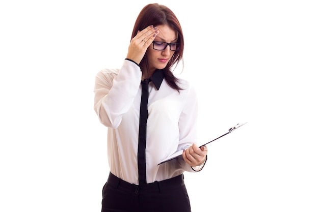 Foto giovane donna affascinante in camicia bianca con lunghi capelli scuri che tiene occhiali neri in studio