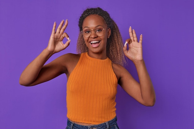 Photo young cheerful african american woman demonstrates ok gesture stands in studio