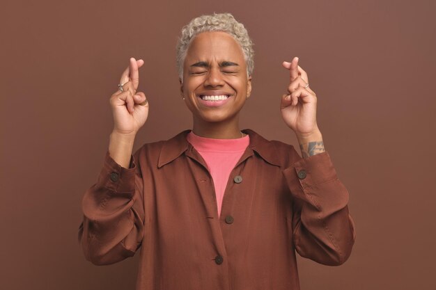 Young cheerful african american woman makes cross with fingers stands in studio