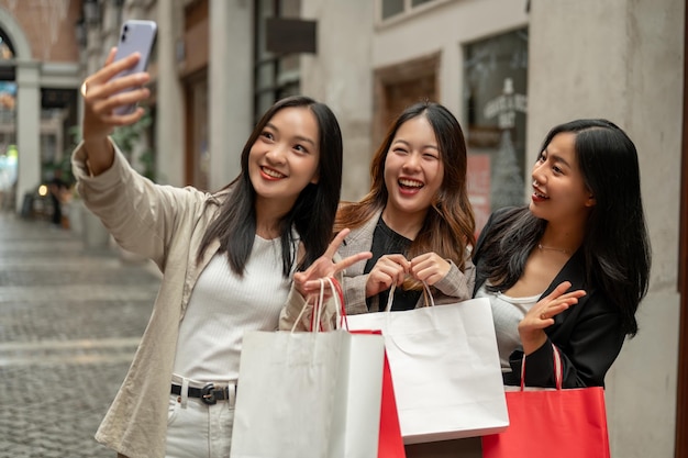 Photo young cheerful asian girls are taking selfies while enjoying their shopping day together