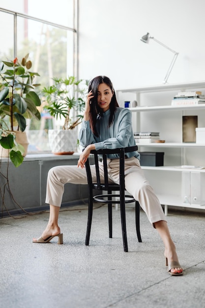 Young cheerful Asian woman sitting in a bright room with plants