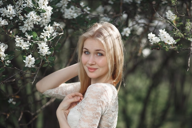 Young cheerful blonde enjoying blossom apple garden. Blooming spring, love, happiness concept