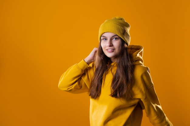 A young cheerful brunette in bright clothes is dancing and having fun a young woman in a yellow hood...