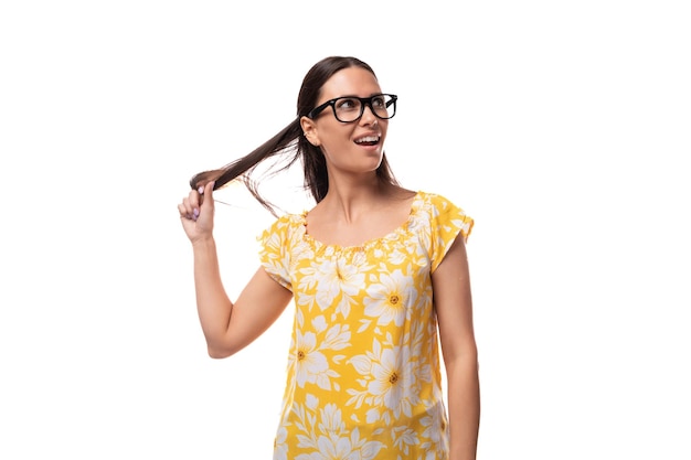 Young cheerful brunette lady with glasses dressed in a yellow sundress