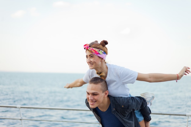 Young cheerful couple in love fooling around on the promenade on the beach