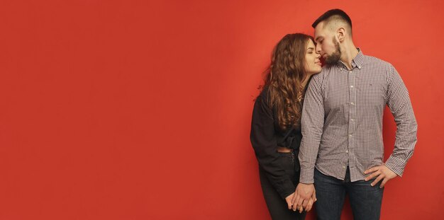 Young cheerful couple in love standing on a red background