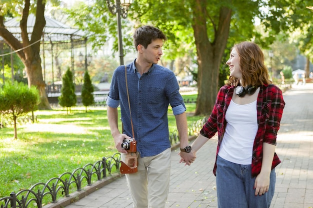 Young cheerful couple of lovers holding hands walking around the city