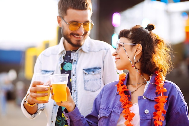 Young and cheerful couple at music festival Happy friends drinking beer and having fun