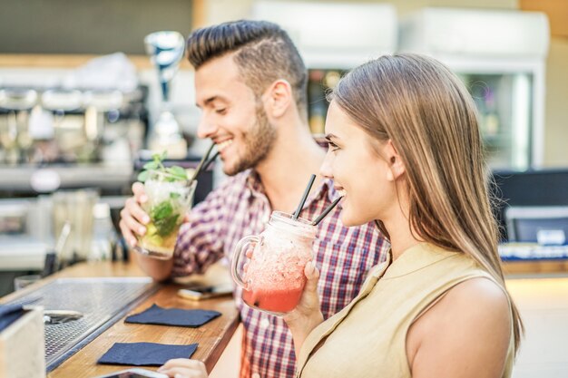 Young cheerful couple toasting cocktails in miami lounge disco bar