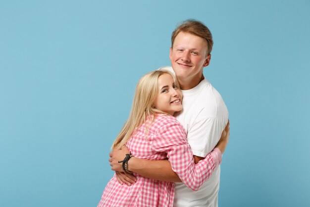 Young cheerful couple two friends guy girl in white pink empty blank design t-shirts posing 