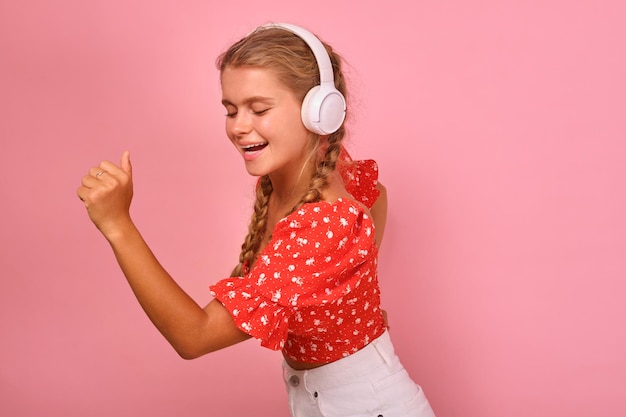 Young cheerful dancing caucasian woman in headphones makes energetic movements