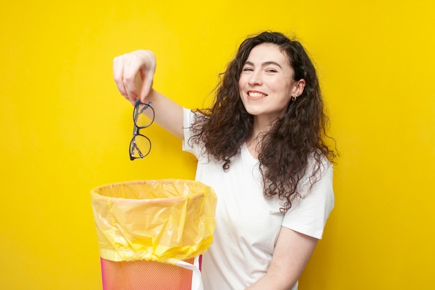 Young cheerful girl throws glasses into trash can the concept of treatment and vision correction