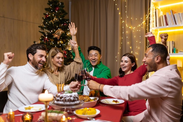 Young cheerful group of interracial people celebrating the coming new year they sit at the festive