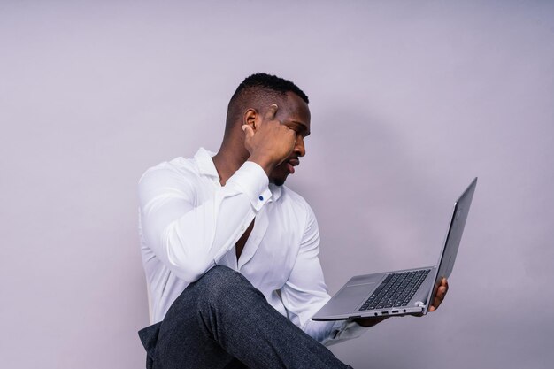 Foto giovane uomo allegro e felice di etnia afroamericana portatile computer portrait studio