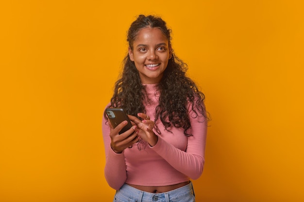 Young cheerful indian woman teenager with phone in hands smiles stands in studio