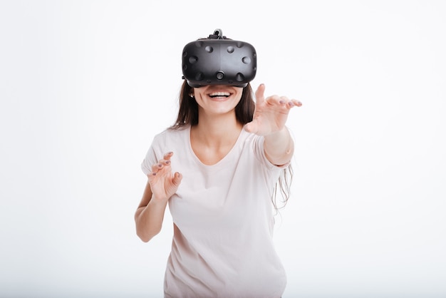 Young cheerful lady wearing virtual reality device .