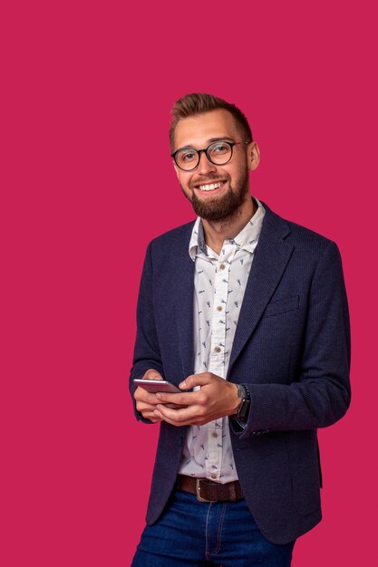 Young cheerful lawyer or businessman is standing on the pink background and smiling reading good new...