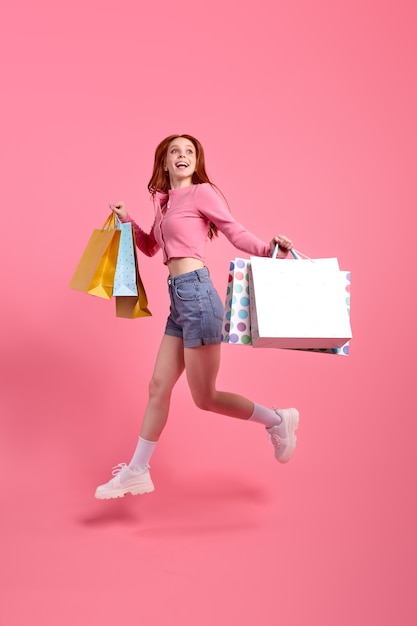 Young cheerful lovely funny funky lady holding packages enjoy rejoice shopping dressed lightcolored ...