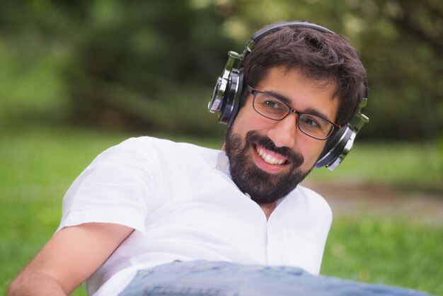 Young cheerful man listening music in the park