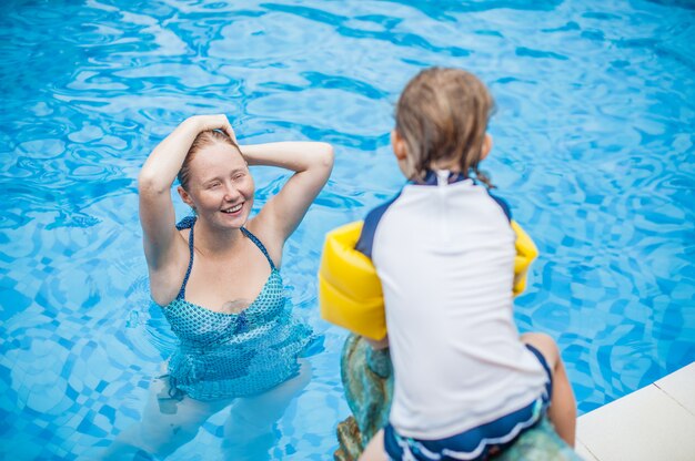 若い陽気な母と息子のスイミングプール