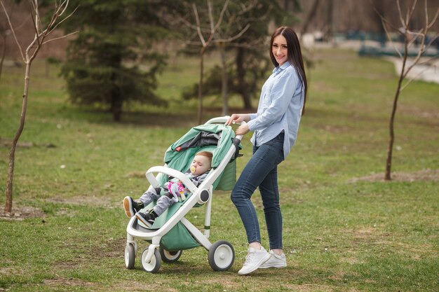 Giovane madre allegra che cammina con il suo bambino in carriege