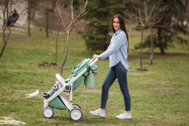 Young cheerful mother walking with her child in carriege