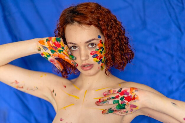 カラフルな塗料で汚れた陽気な赤毛の若い女性