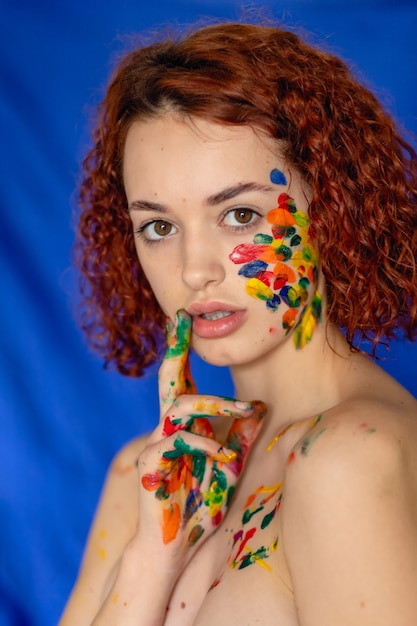 Foto giovane donna dai capelli rossi allegra sporca di vernice colorata