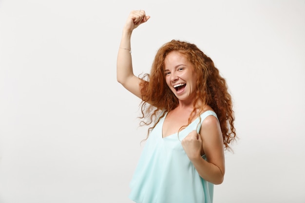 Young cheerful redhead woman girl in casual light clothes posing isolated on white wall background studio portrait. People sincere emotions lifestyle concept. Mock up copy space. Doing winner gesture.