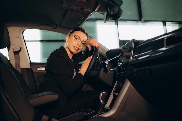 Young and cheerful woman enjoying new car hugging steering wheel sitting inside Woman driving a new car Woman Driver Portrait at Car