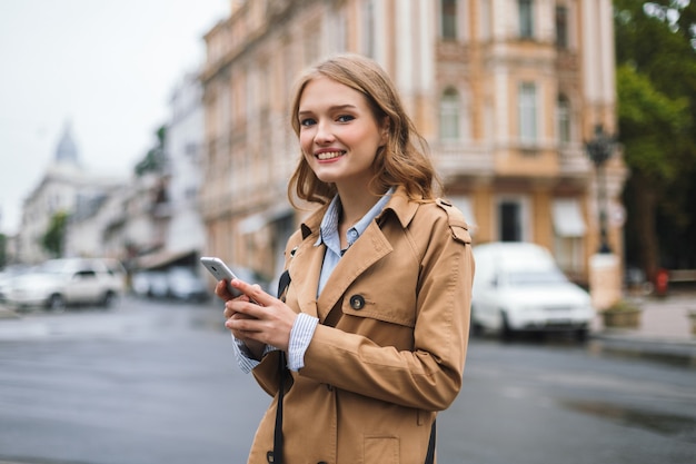 Young cheerful woman in trench coat happily 