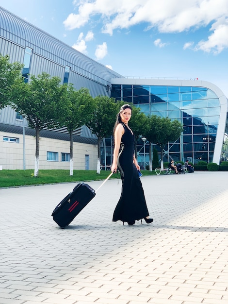 Young Cheerful Woman With a Suitcase. The  of Travel and work