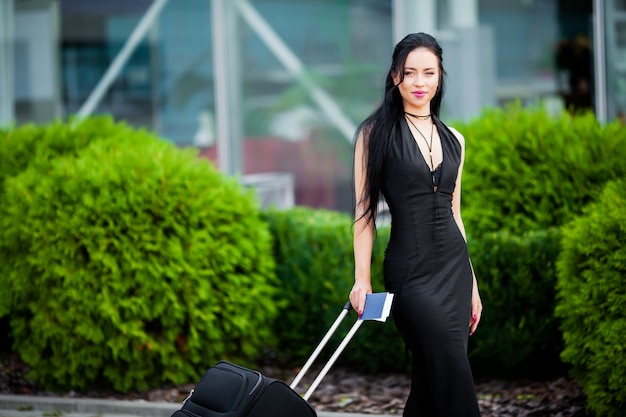 スーツケースを持つ若い陽気な女性。旅行と仕事の