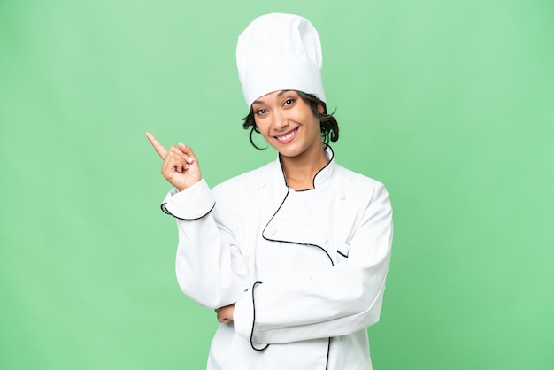 Young chef Argentinian woman over isolated background pointing finger to the side