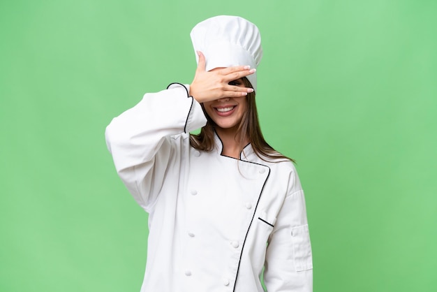 Young chef caucasian woman over isolated background covering eyes by hands and smiling