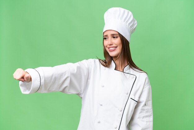 고립된 배경 위에 엄지손가락을 치켜드는 젊은 요리사 백인 여성