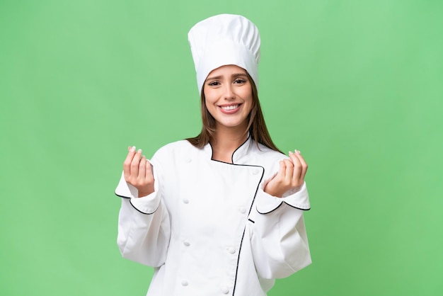 Giovane chef donna caucasica su sfondo isolato facendo gesto di denaro