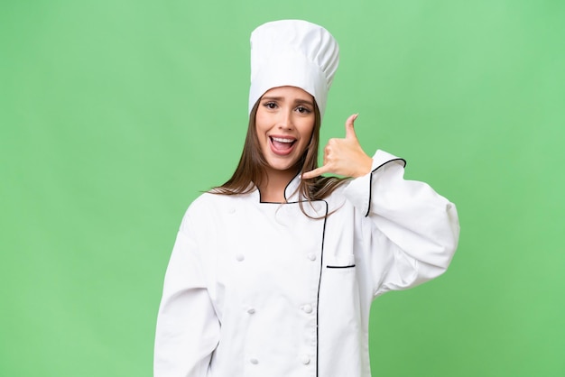 Young chef caucasian woman over isolated background making phone gesture Call me back sign