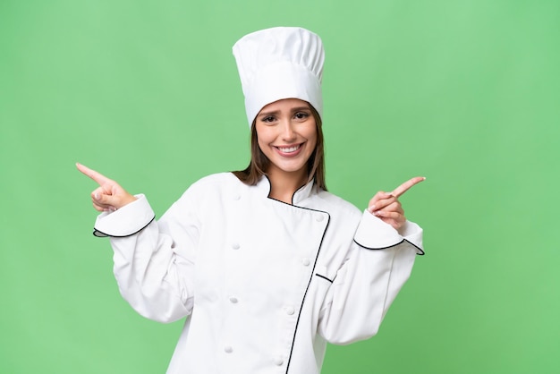 Young chef caucasian woman over isolated background pointing finger to the laterals and happy