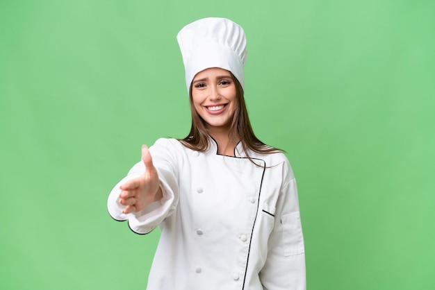 Молодой шеф-повар кавказской женщины на изолированном фоне пожимает руку за заключение хорошей сделки