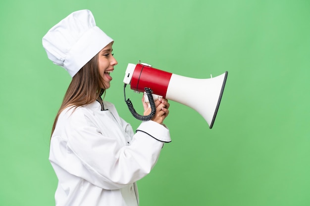 Young chef caucasian woman over isolated background shouting through a megaphone