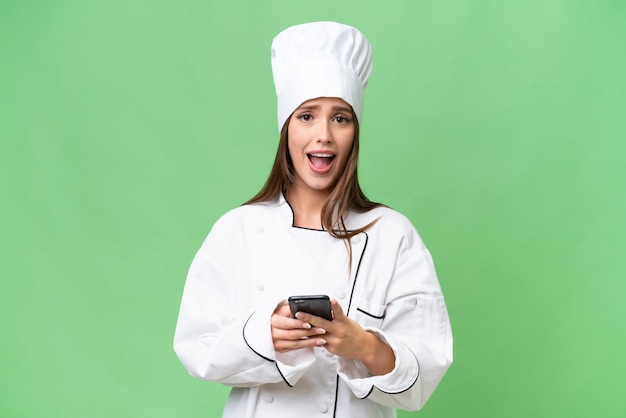 Young chef caucasian woman over isolated background surprised and sending a message