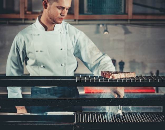 Young chef cooking beef steak in a professional kitchen