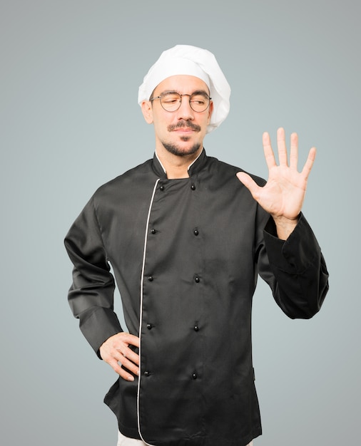 Young chef making a number five gesture