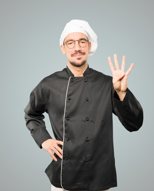 Photo young chef making a number four gesture