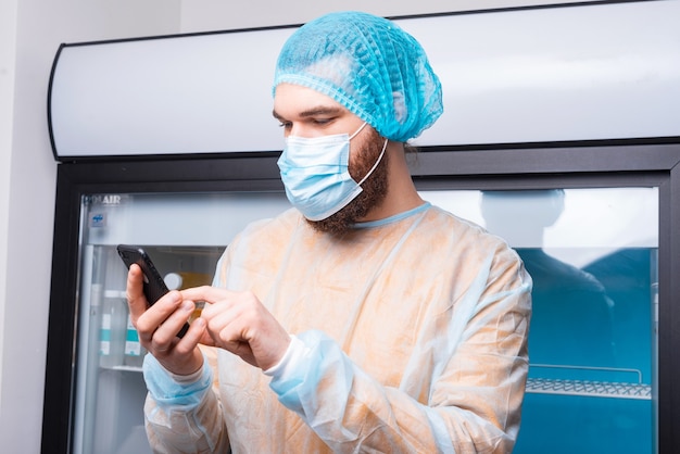 Giovane chef uomo in cucina utilizza lo smartphone durante il covid-19