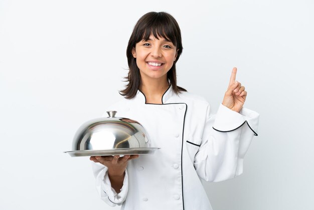 Young chef with tray isolated on white background pointing up a great idea