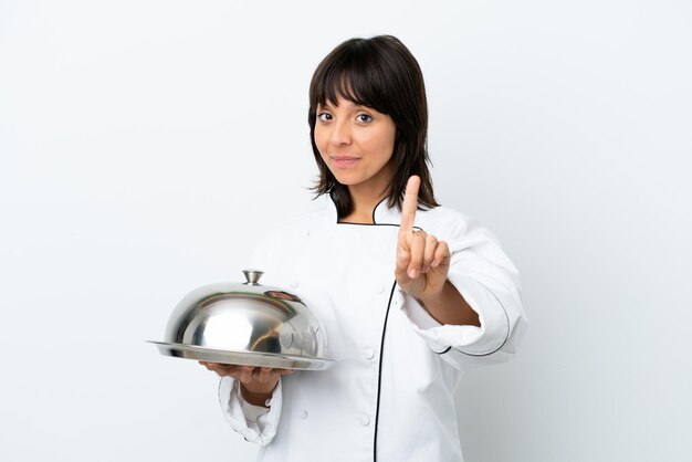 Молодой шеф-повар с подносом на белом фоне показывает и поднимает палец