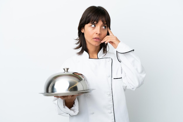 Young chef with tray isolated on white background thinking an idea