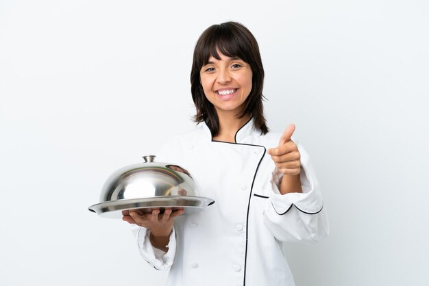 Young chef with tray isolated on white background with thumbs up because something good has happened